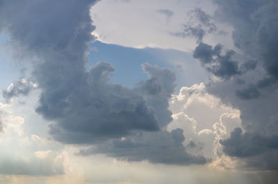 Low angle view of sunlight streaming through clouds