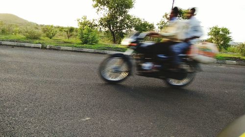Blurred motion of man riding motorcycle on road