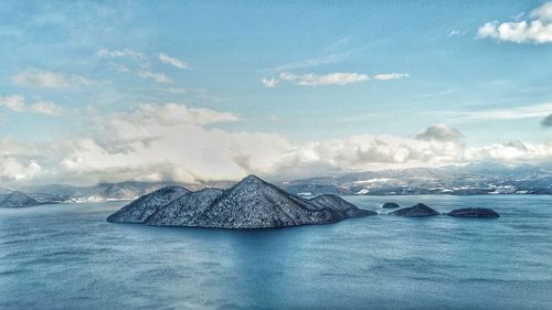 Scenic view of sea by snowcapped mountain against sky