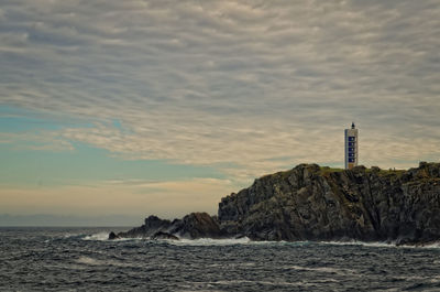 Lighthouse by sea against sky