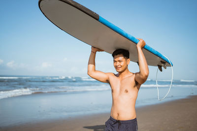 Rear view of man with arms outstretched standing at beach