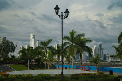 Street amidst trees and buildings against sky