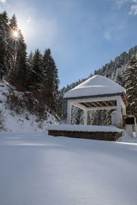 Built structure on snow covered land and trees against sky