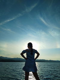 Rear view of man standing in sea against sky