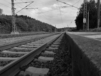 Empty railroad tracks amidst trees against sky