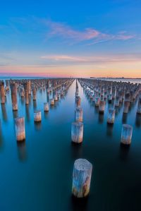 Wooden posts in sea against sky