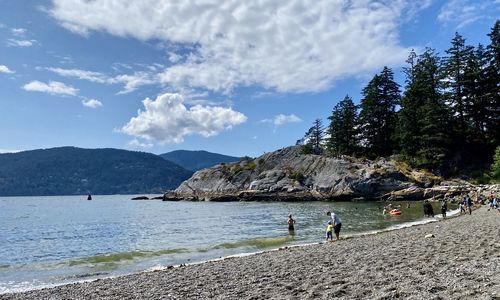 People on beach by mountain against sky