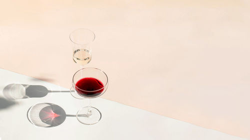 Glasses of red and white wine with hard shadows on the background.