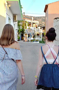 Rear view of friends walking on street in city