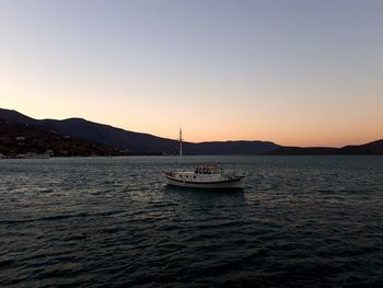 Boat sailing on sea against clear sky during sunset