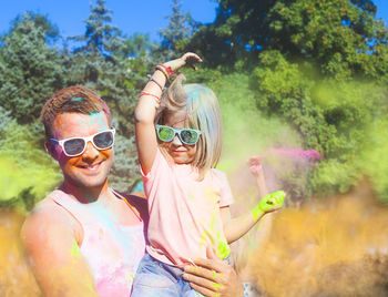 Smiling father holding daughter while playing holi