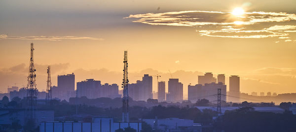 Silhouette buildings in city against sky during day