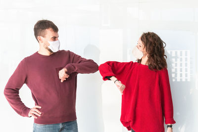 Young man and woman standing against red wall