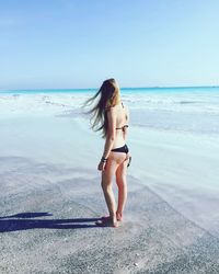 Full length of woman in bikini standing on beach against sky