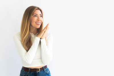 Portrait of young woman standing against white background