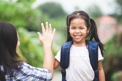 Portrait of smiling girl doing high-five with mother