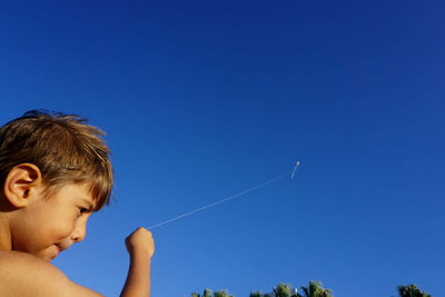 Boy flying kite against sky