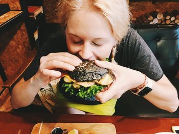 High angle view of woman eating hamburger at restaurant