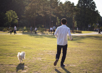 Rear view of man with dog on field