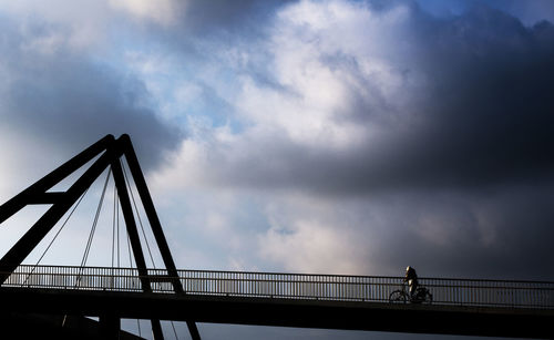 Silhouette of suspension bridge against sky