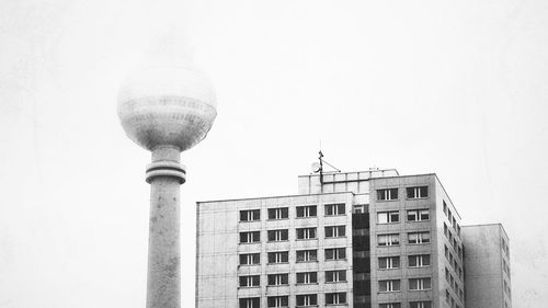 Communications tower in city against clear sky