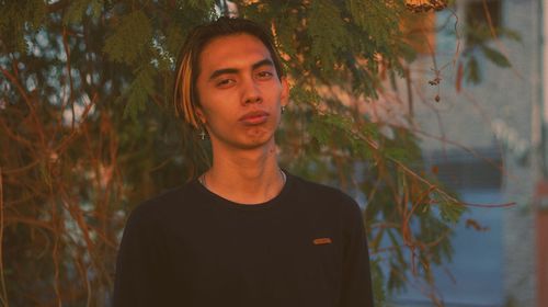 Portrait of young man standing against trees