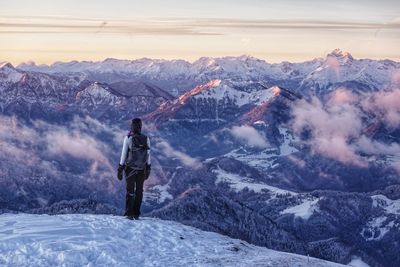 Rear view of man standing on snowcapped mountain