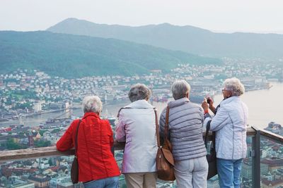 Rear view of people standing by sea against cityscape