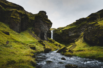 Scenic view of waterfall amidst rocks against sky