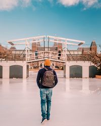 Rear view of man standing on bridge against sky