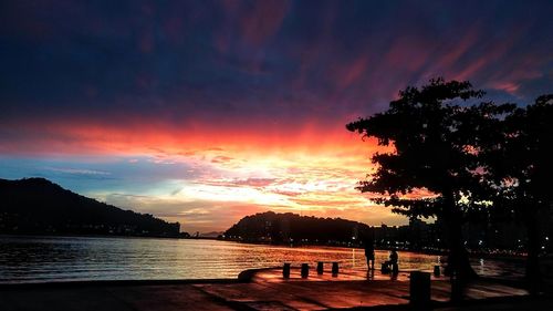 Silhouette trees by lake against sky during sunset