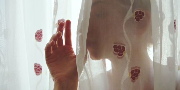 Close-up of thoughtful woman covered with white curtain