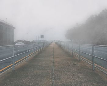 Road in city against sky during foggy weather