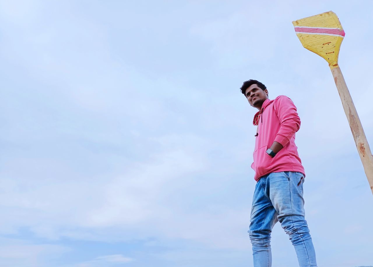 LOW ANGLE VIEW OF YOUNG MAN LOOKING AT SKY