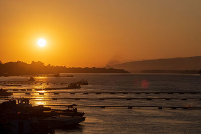 Scenic view of river against orange sky. sand extraction, sand suction boats.