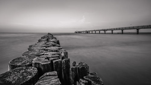 Wooden posts in sea against sky