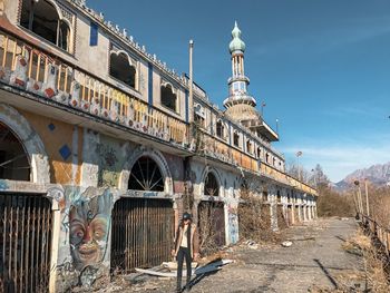 Full length of woman wearing cap walking by old building