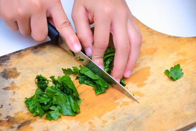 Close-up of hand holding vegetables on cutting board