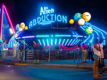 People at amusement park ride at night