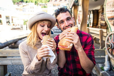 Young couple eating food in city