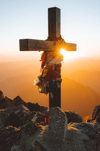 Rear view of man standing on rock against sky during sunset