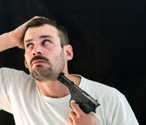 Man attempting suicide with gun against black background