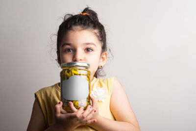 Little girl holding a pickled pepper conserve at hands