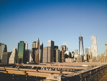 World trade center with modern buildings seen from brooklyn bridge against clear sky