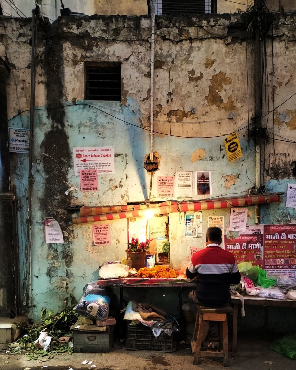 urban area, road, street, architecture, built structure, art, building exterior, seat, city, infrastructure, chair, day, building, sitting, adult, furniture, old, men, one person, table, person, alley, occupation, wall, outdoors, wall - building feature, messy