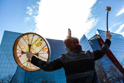 Low angle view of man holding sculpture against sky