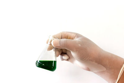 Close-up of hand holding bottle against white background