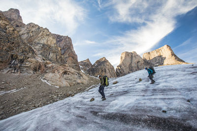 Two mountain climbers traverse a glacier below mount asgard.