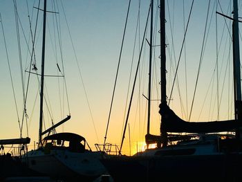 Silhouette sailboats on marina at sunset