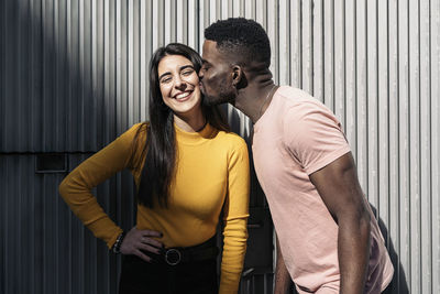 Man kissing woman against wall